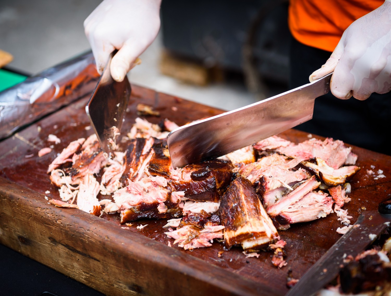 Chef Hands cutting Grilled spare beef or pork back ribs prepared in smoker with a hatchet at the Frisco BBQ Festival
