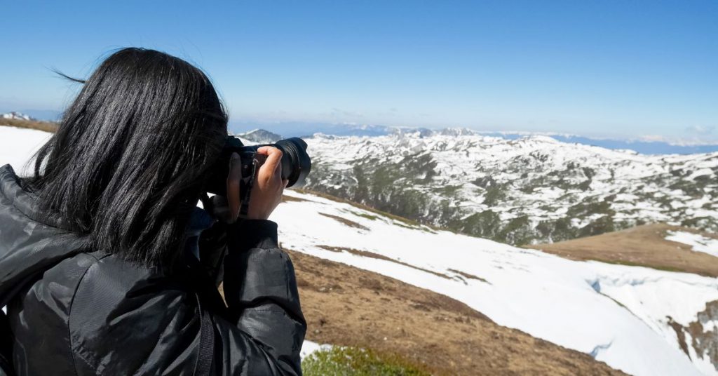 girl taking a photo of the snowy mountains