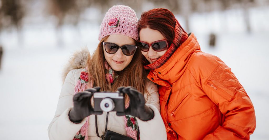 two women taking photos on the snow